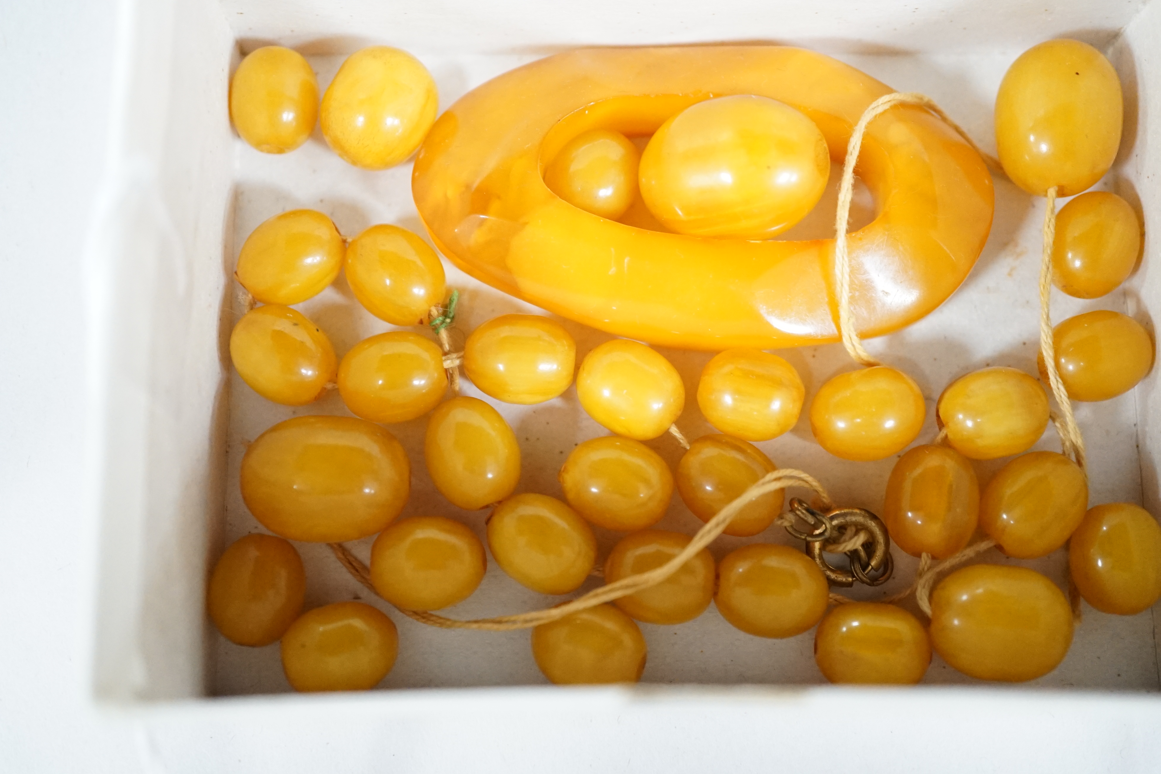 A small amber openwork pendant, 62mm, 12 grams and a group of simulated amber beads. Condition - poor to fair